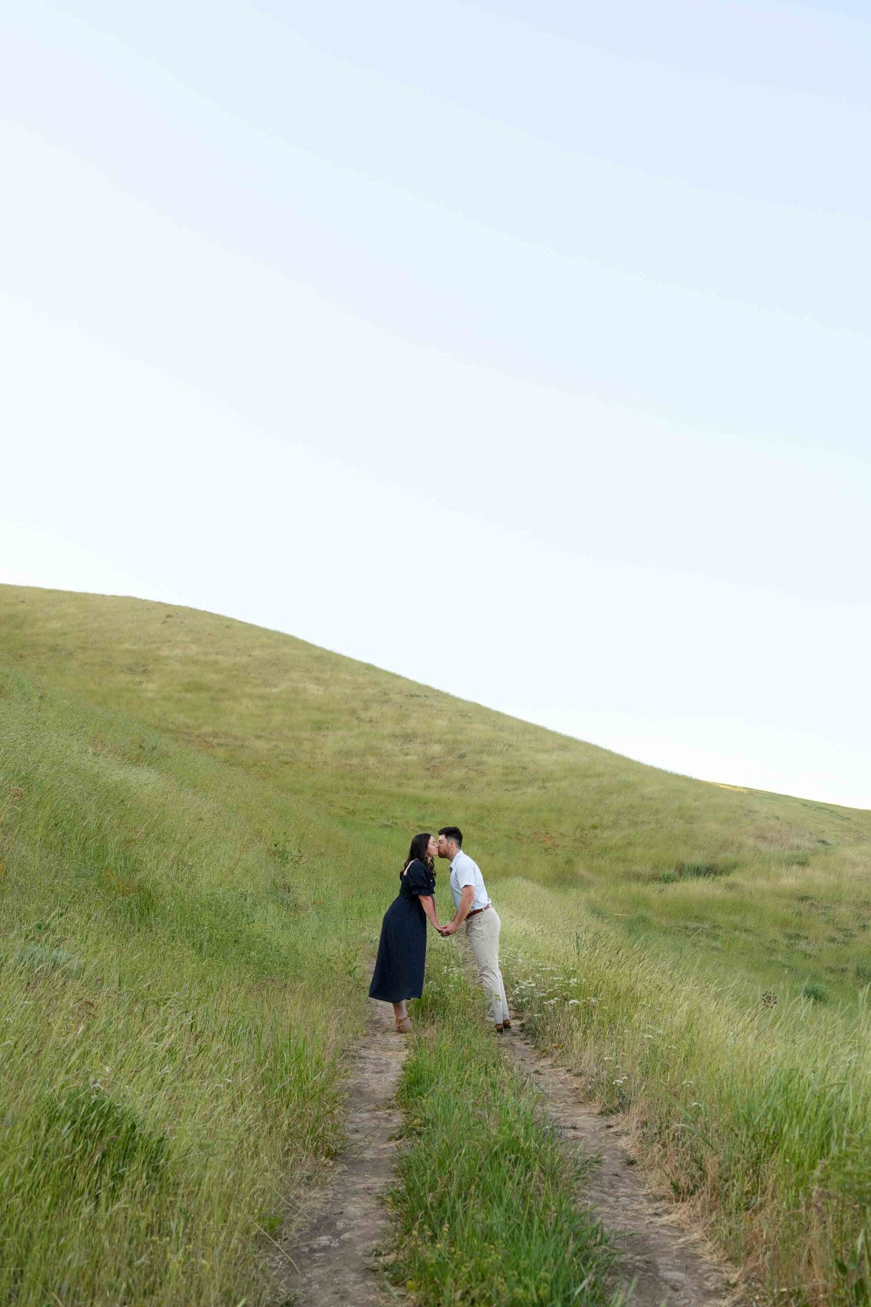 Alyssa and Jacob during their engagement session at Nahahum Trail in Cashmere, Washington with rolling hills and meadow views