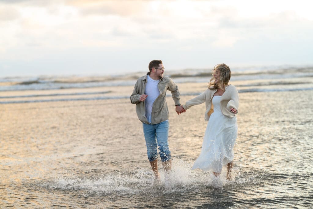 A couple walking hand-in-hand through shallow ocean water during their Seabrook Washington engagement session on the beach before their Mt Rainier elopement.