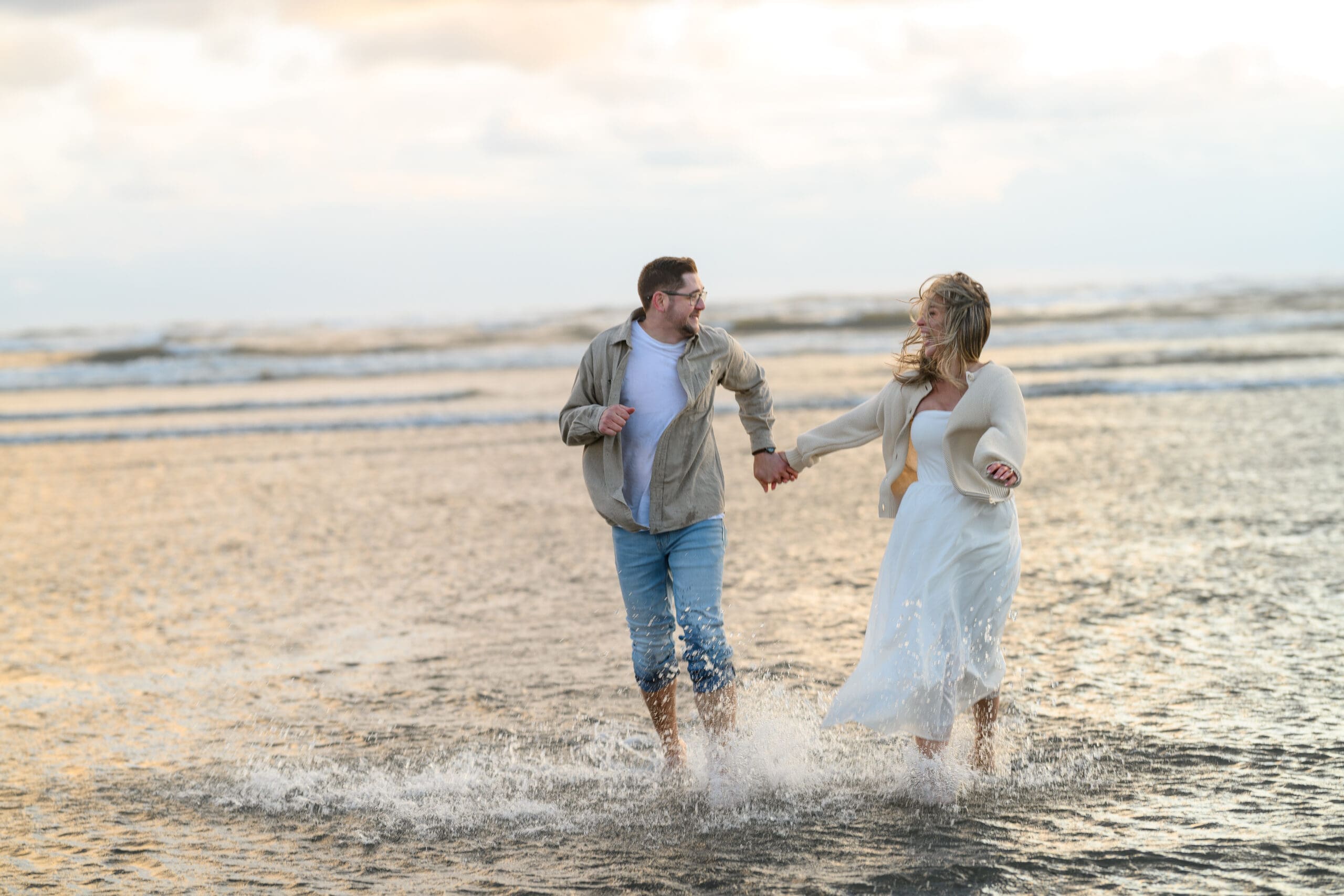 A couple walking hand-in-hand through shallow ocean water during their Seabrook Washington engagement session on the beach before their Mt Rainier elopement.